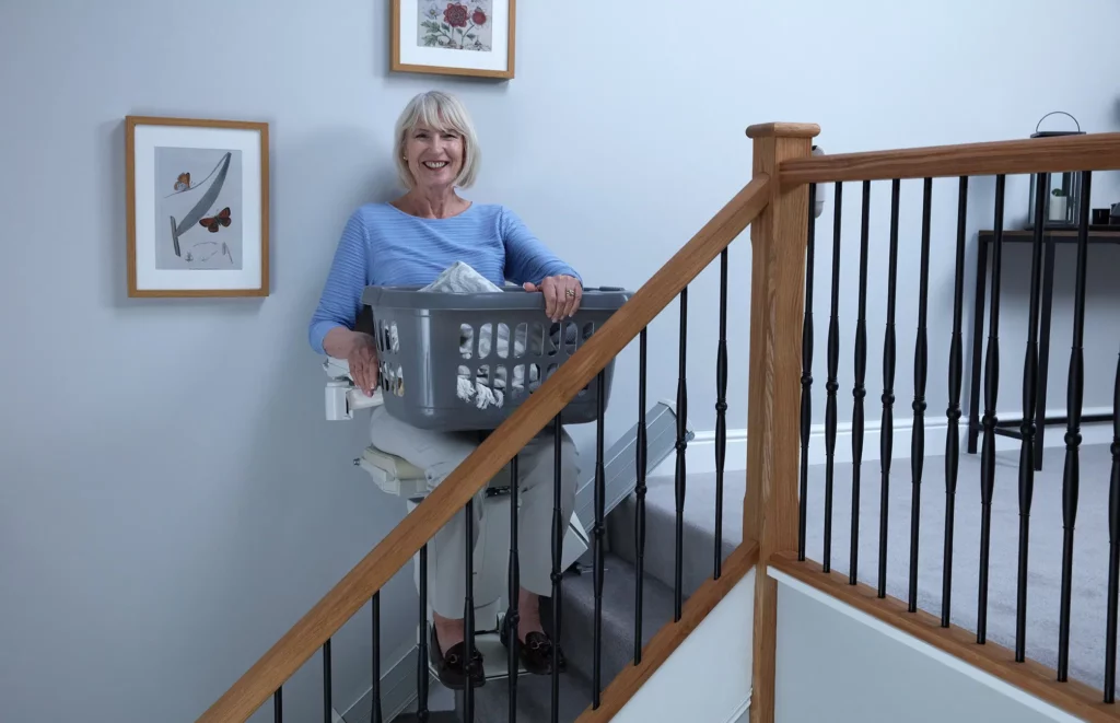 Lady on a straight stairlift carrying laundry basket
