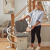 image of a woman adjusting her stairlift at her property in chelmsford, essex , image has woman standing on hardwood floor
